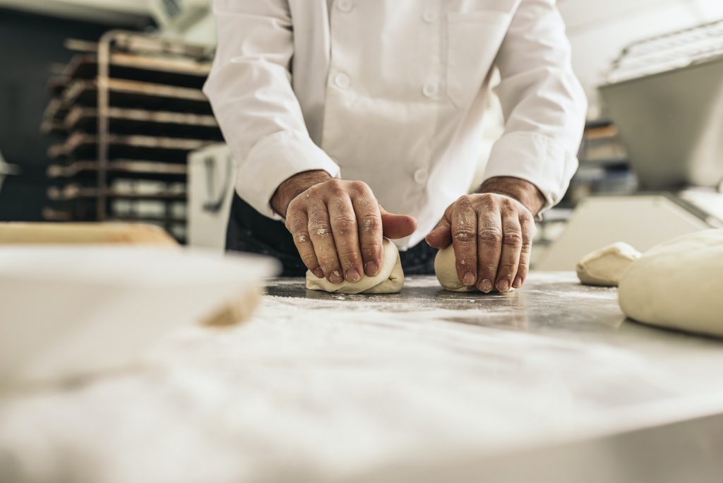 Baker kneading dough in a bakery.